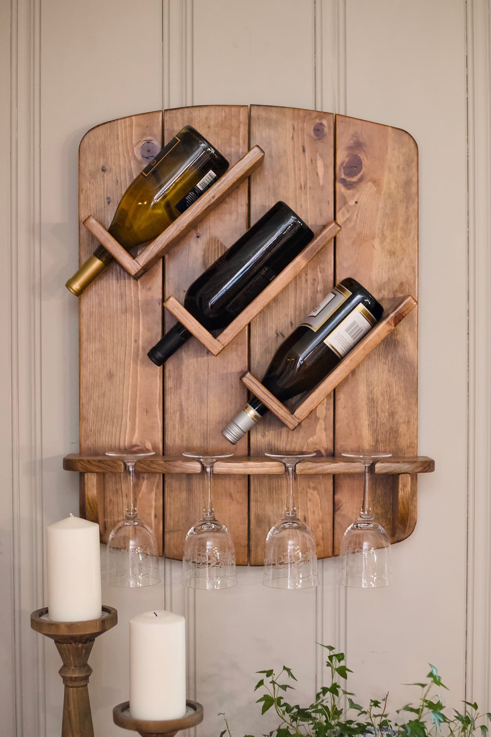 Wine rack mounted on a wall holding bottles and glasses
